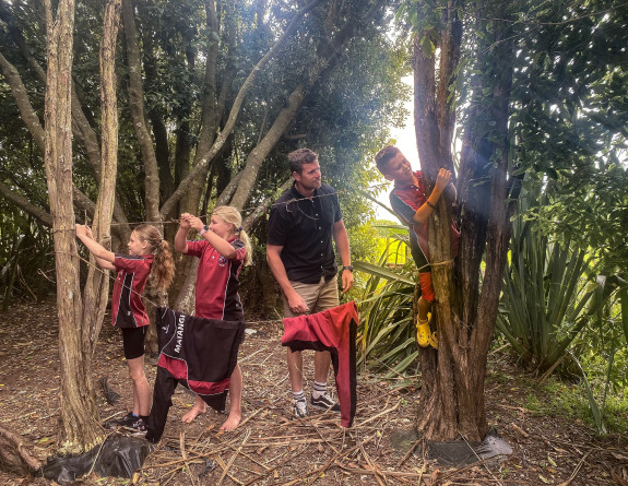 Students at Matangi School learn how to tie double knots with harakeke plants and create a washing line at ‘Bush School’.