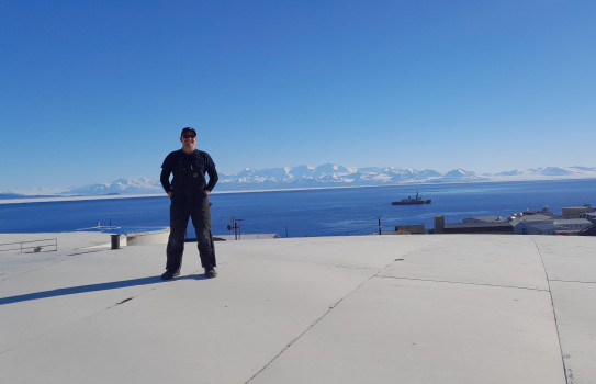 CPL Mitchell Taylor standing at ease on top of one of the five 7,560,000 litre tanks overlooking McMurdo Station in Antarctica on a sunny day.