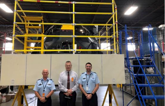 Members of the project team stand in front of the simulator being built. 