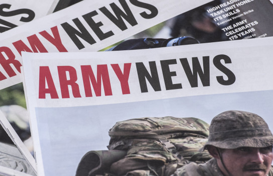 Three editions of Army News stacked a table