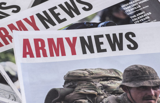 Three editions of Army News stacked a table