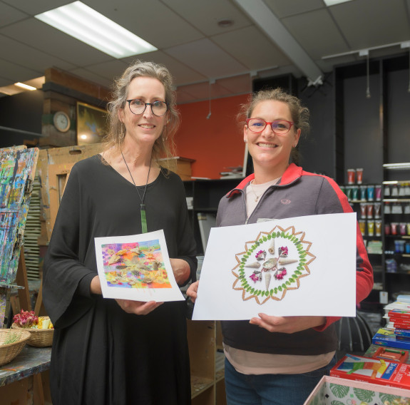 Two people holding the colourful artwork they have created.