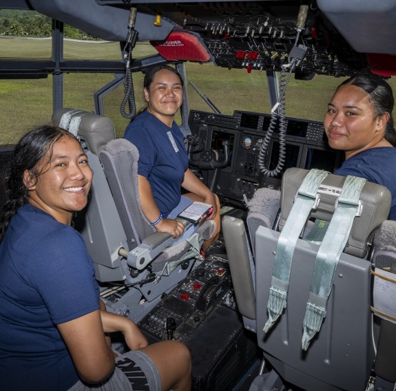 Three students in the cockpit of a Hercules aircraft.