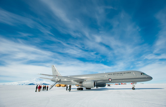 A large grey jet aircraft lands at Pegasus Airfield on the Ross Ice Shelf under broken clouds and blue skies. 