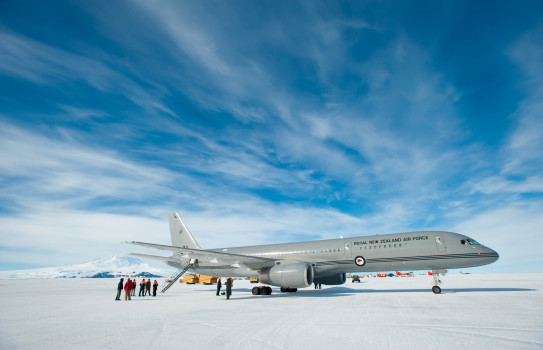 A large grey jet aircraft lands at Pegasus Airfield on the Ross Ice Shelf under broken clouds and blue skies.