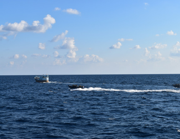 Two small boats move through the water behind another boat. On a sunny day.