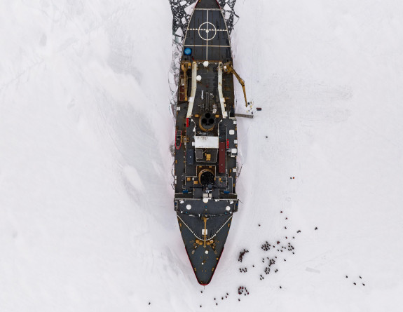 A birds eye view of the USCGC Polar Star stationary as the ship was breaking through the ice. There are black dots at the bow of the ship, this is the crew as they disembarked for a morale boost.