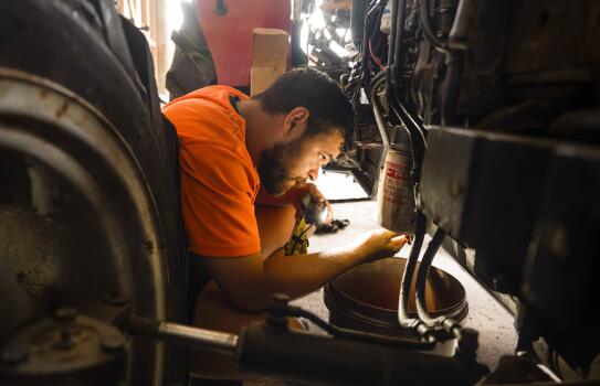 A man uses a torch to look underneath a vehicle