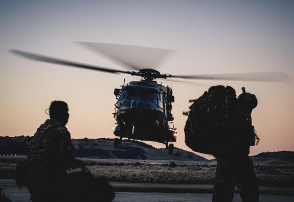 Reserve Force soldiers silhouetted with an NH90 helicopter coming down to land in the background. 