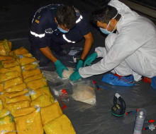 Multiple drug packages lined up on board French ship FS Floreal, as personnel expertly handle them in protective gear.