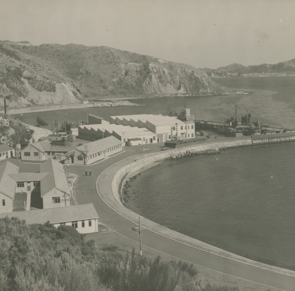 A black and white photograph of Shelly Bay (looking South from the hills) shows a tidy base with clean roads and maintained buildings along a curved coastal road.