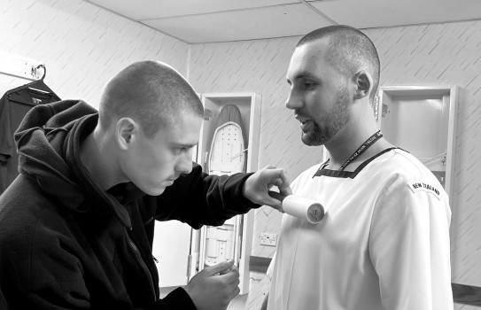 Navy recruits help each other remove lint from uniform with a lint roller prior to inspection.