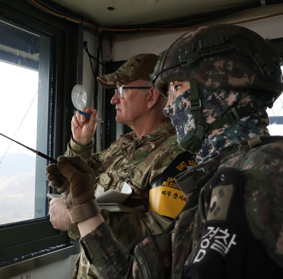 Two soldiers look out a window.