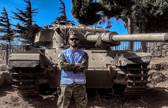 Peacekeeper standing in front of destroyed tank