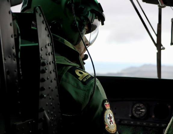 A pilot in the cockpit looks to his right, the windscreen and a faint horizon are in the background.