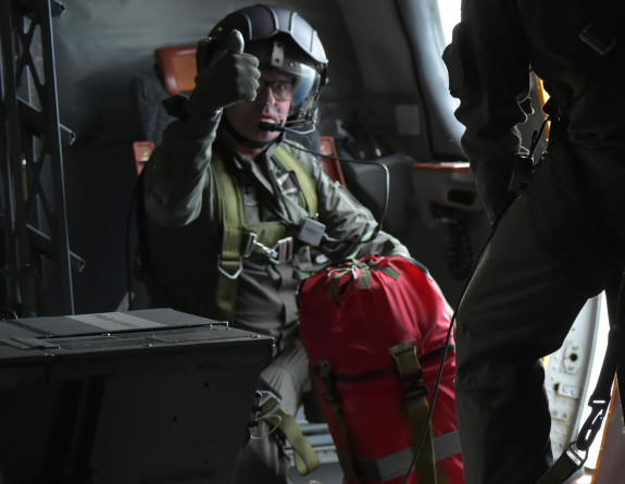 A member of the Orion crew gives a thumbs up as they prepare to drop a survival pack to those on board.