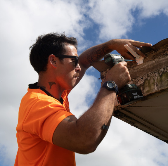 Lance Corporal Eddie Wright works on the guttering of a community hall in Tonga, helping the island kingdom in its ongoing recovery from last year’s volcanic eruption.