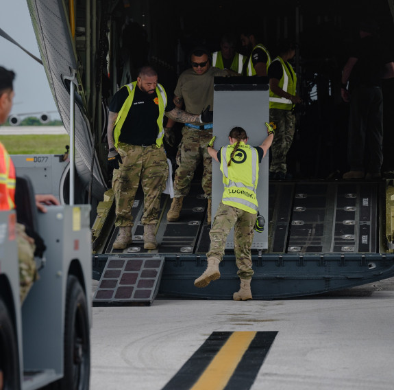 Aviators unload cargo from the back of an aircraft.