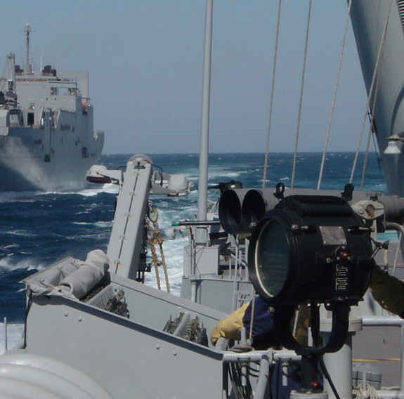 A HMNZS Te Kaha sailor on watch as the frigate escorts the USNS WATKINS, a logistics roll-on, roll-off vessel.