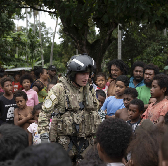 A Royal New Zealand Air Force aviator talks with a large group of locals in Papua New Guinea.