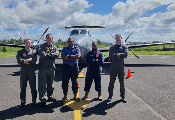 People standing in front of an aircraft - arms crossed on a sunny day with clouds. 
