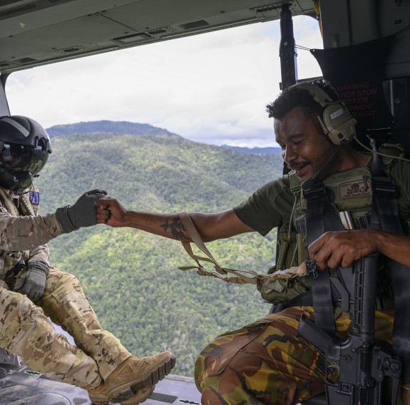 An Aviator from the Royal New Zealand Air Force fist bumps a soldier from Papua New Guinea in an NH90 helicopter as it flies above the highlands.