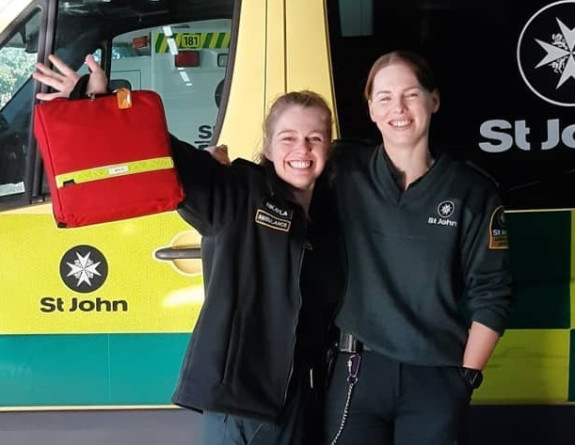 Two people stand in front of an ambulance. 