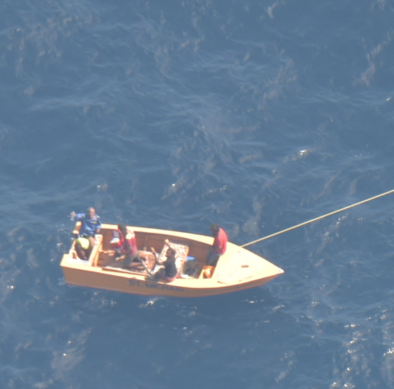 An aerial photo of a small boat with off Kiribati with three men on board.