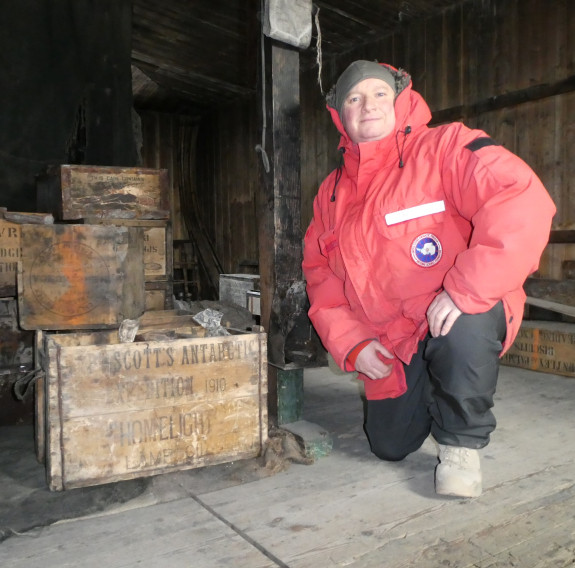 New Zealand Army Reserve Force combat driver Sergeant Justin Dark knells on one knee next to some wooden boxes. 