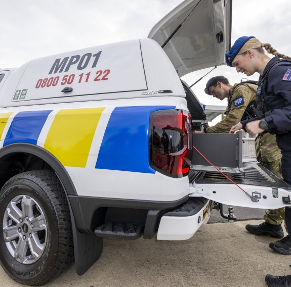Two members of the Military Police access the trunk of one of the vehicles.