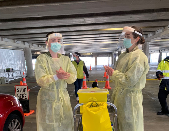 NZ Army medics in protective equipment sanitise their hands as they vaccinate people in their vehicles in the Wellington's Sky Stadium carpark.