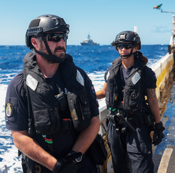 Two sailors not looking at the camera on board a vessel