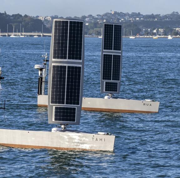 Two USVs at sea in front of the shore in the distance.