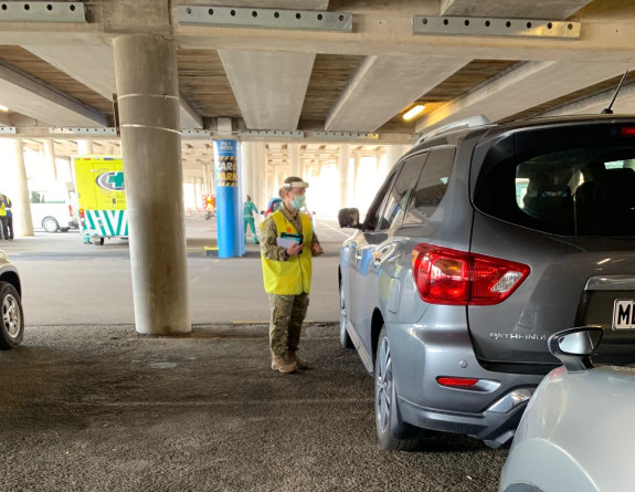A NZ Army medic gathers information from people in their vehicles, waiting in line for vaccination in Wellington's Sky Stadium carpark.