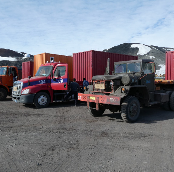 Various trucks lined up in a row with containers on the back. 