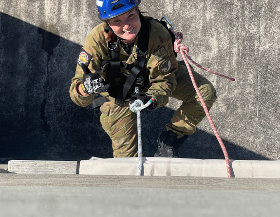 A RNZAF aviator repels down the side of a building.