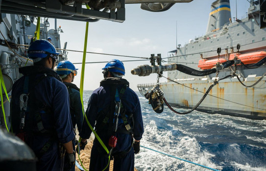 Sailors on HMNZS Te Kaha (left) oversea the probe moving down the spanwire from USNS Guadalupe (right) as both ships sail alongside each other.