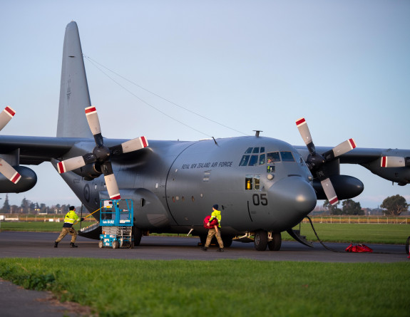 Hercules aircraft on the flight line with personnel in high vis on the ground prepping for flight. 