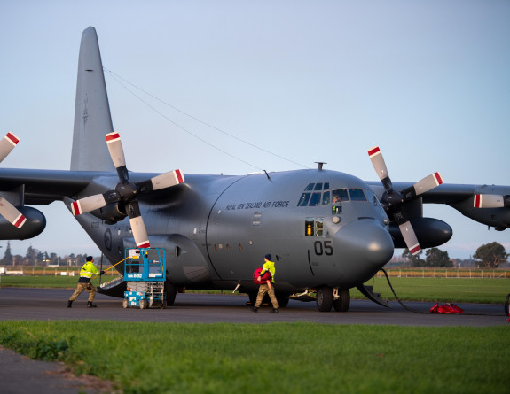 Hercules aircraft on the flight line with personnel in high vis on the ground prepping for flight.