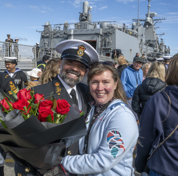 Sailors reunite with loved ones in front of the ship at Devonport Naval Base.