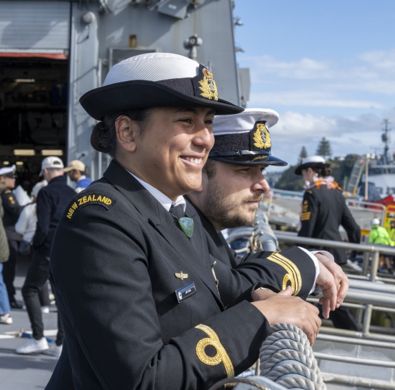 Two sailors watch reunions from the flight deck of the ship.