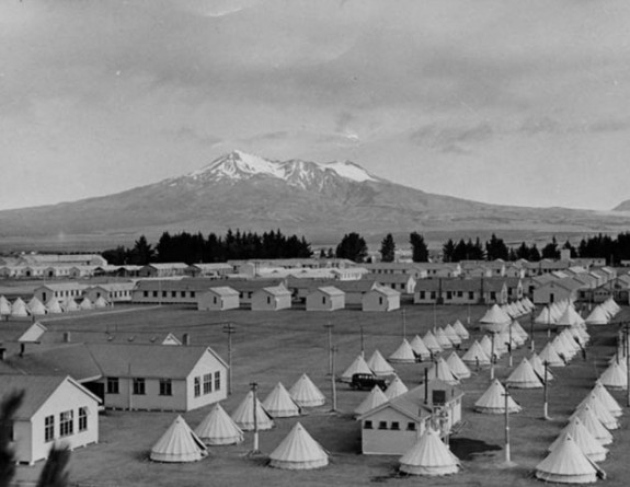 Waiouru Military Camp in 1940-1941 with a mixture of bell tents and wooden huts, with Mount Ruapehu in the background.