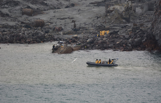 New Zealand Defence personnel wearing yellow suits on a zodiac boat at White Island / Whaakari