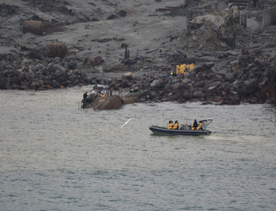 New Zealand Defence personnel wearing yellow suits on a zodiac boat at White Island / Whaakari