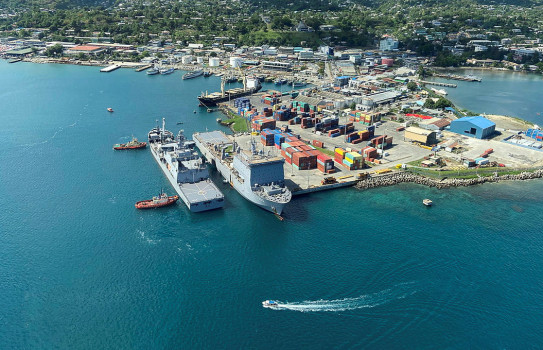 Arial view of two grey military ships alongside each other at a port.