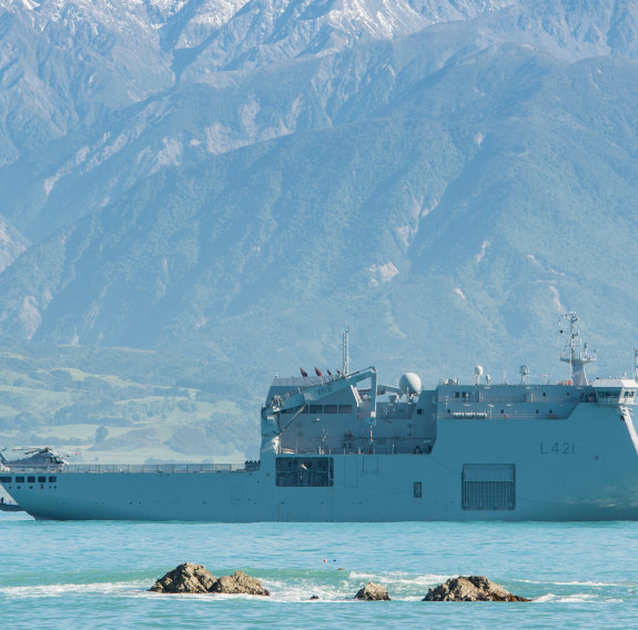 HMNZS Canterbury at sea, green New Zealand hills in background