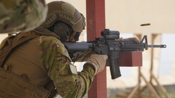 An Aviator fires a MARS-L rifle while leaning the weapon on a red beam. A shell flies out of the right of the rifle.